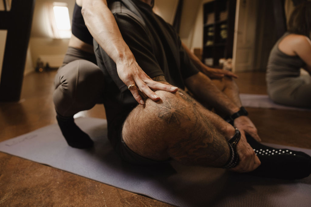 Deelnemer in een diepe yogastretch op de mat in De Shala