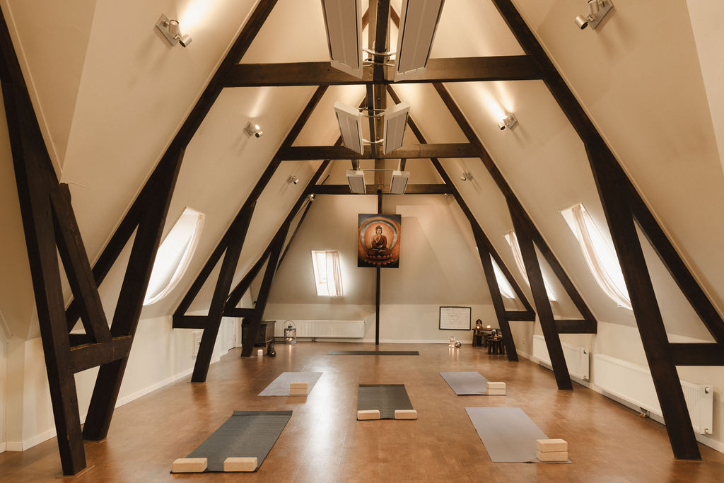 De Shala: yogazaal met matten onder de houten spanten