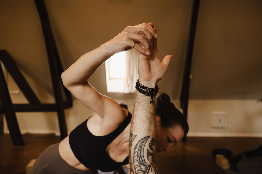 Yogadocent strekt haar arm boven het hoofd in De Shala