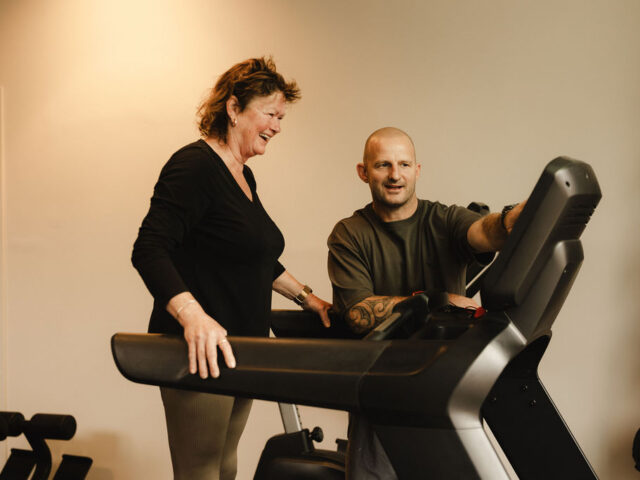 Personal trainer begeleidt een deelnemer op de loopband